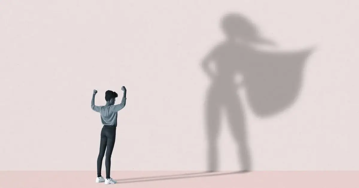 Illustration representing a small figure raising their arms in a triumphant pose, casting a large silhouette shadow on the wall behind them depicting a superhero wearing a cape